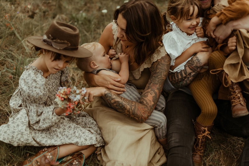 Newborn Photography, Family sitting close together in a field while mom breastfeeds