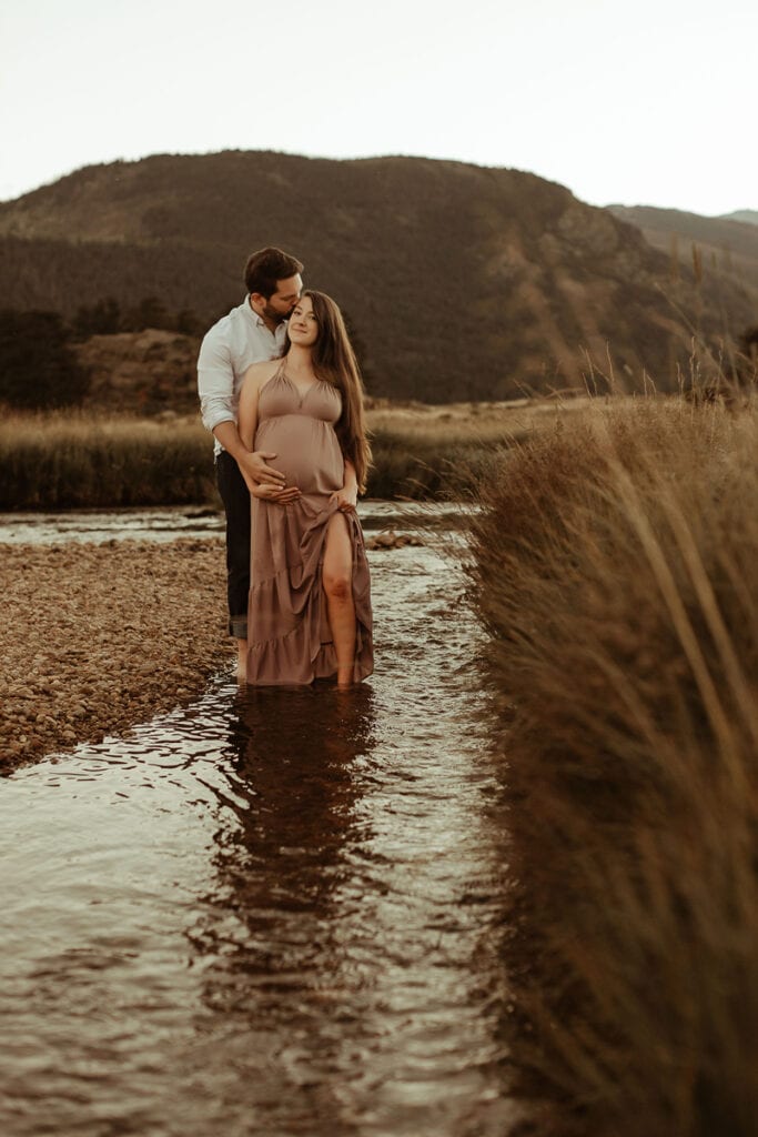 Maternity Photography, man and woman standing in water, she holds her belly