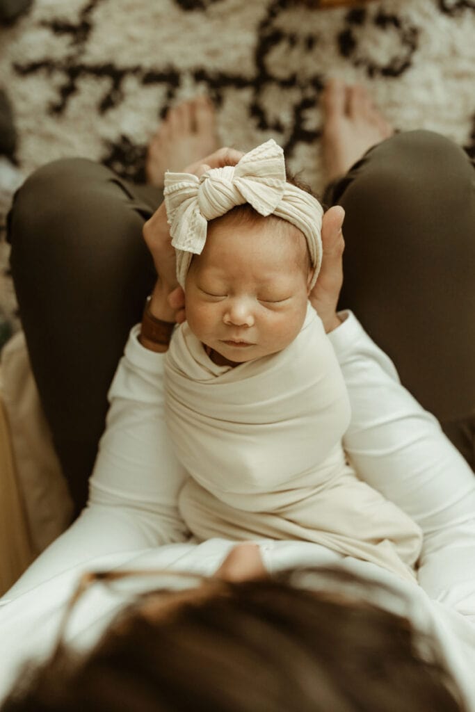 Newborn Photography, looking down on a newborn baby wearing a bow