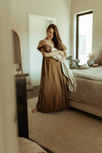 A woman stands and sways with her baby at her home newborn session.